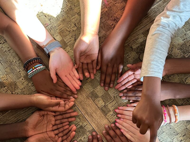 Se muestran 16 manos en un círculo durante el campamento de las Mujeres Jóvenes de la rama Treasure Valley (swahili) en Boise, Idaho, el 5 de junio de 2025.