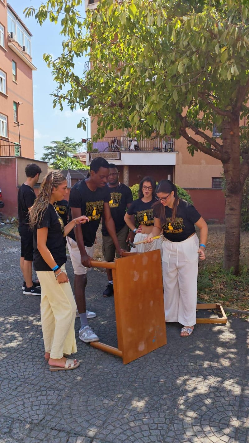 Adultos jóvenes solteros trabajan juntos para desmantelar muebles durante un proyecto de servicio en Casa Scalabrini 634 en Roma, Italia.