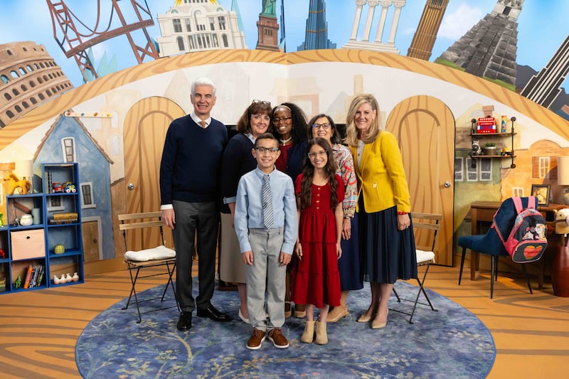 El élder y la hermana Caussé y la presidencia general de la Primaria se toman una foto con dos niños anfitriones durante la grabación de la transmisión Amigo a Amigo de septiembre de 2026.