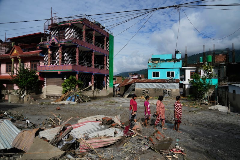 Personas caminan junto a los daños causados por inundaciones repentinas en Devighat, en el distrito de Nuwakot, Nepal, jueves, 27 de agosto de 2026.