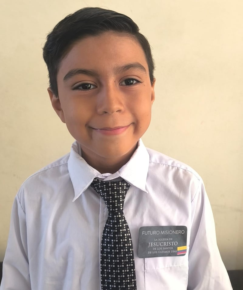 Jorge Mena, de 9 años, sonríe para una foto mientras usa una placa con el nombre "futuro misionero" después de la actividad del centro de capacitación misional en miniatura de la Primaria de la Estaca Samborondón Ecuador, en Guayaquil, Ecuador, el 21 de febrero de 2026.