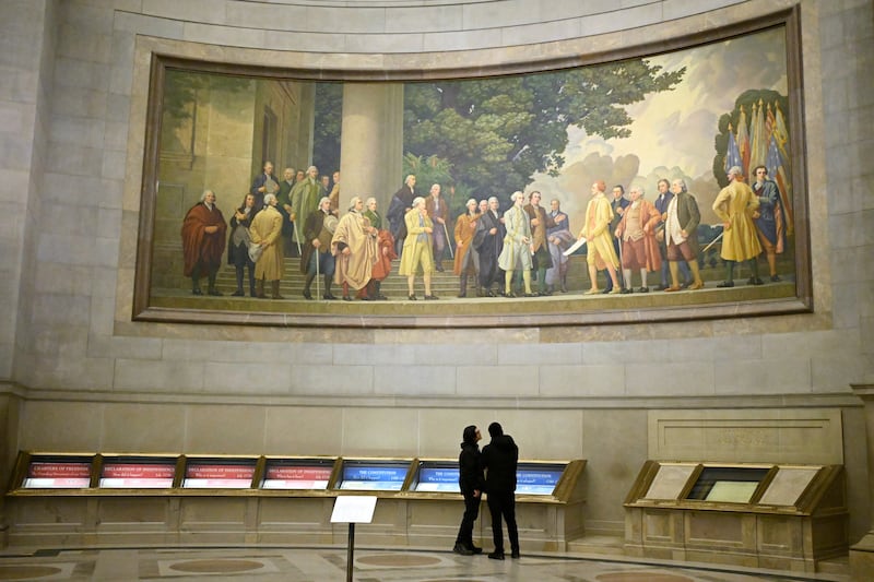 Dos visitantes observan las exhibiciones bajo un gran mural que muestra la firma de la Declaración de Independencia en los Archivos Nacionales, el jueves 29 de enero de 2026, en Washington, D. C.