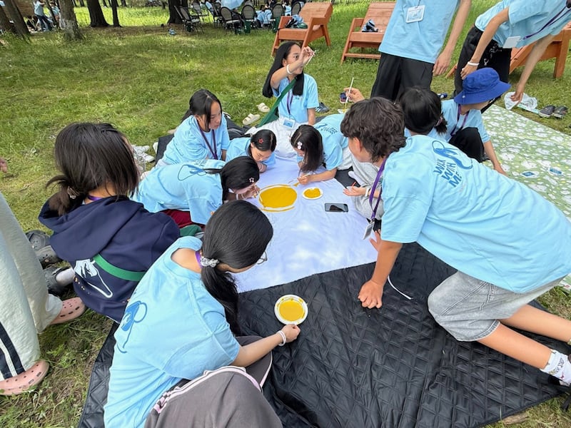Los participantes en una Conferencia Para la Fortaleza de la Juventud cerca de Ulán Bator, Mongolia, crean una bandera de equipo el 28 de junio de 2026.