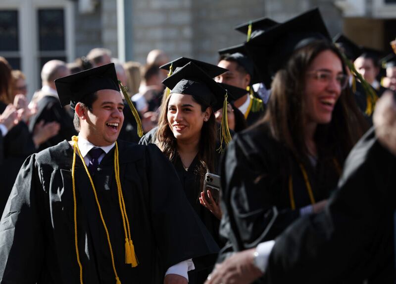 Los graduados se ríen y hablan mientras marchan en procesión hacia el Tabernáculo durante la ceremonia de graduación de Ensign College en el Tabernáculo de la Manzana del Templo en Salt Lake City el viernes 8 de abril de 2022.