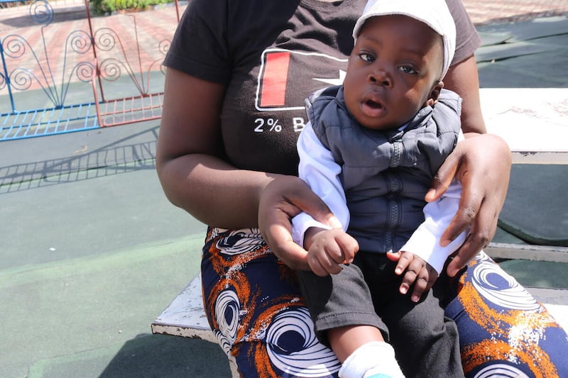 Samuel, de un año de edad, sentado en el regazo de su madre fuera del Hospital General Lewanika en Mongu, Zambia. Nació prematuro en diciembre de 2024.