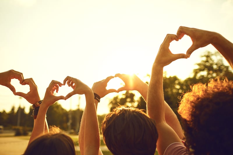 Manos de un grupo de amigos en forma de corazón contra la puesta de sol. Concepto de amor y amistad en las relaciones