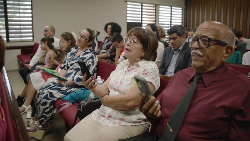 Miembros de la Iglesia en Puerto Rico cantan usando sus teléfonos durante su reunión de sacramiento.