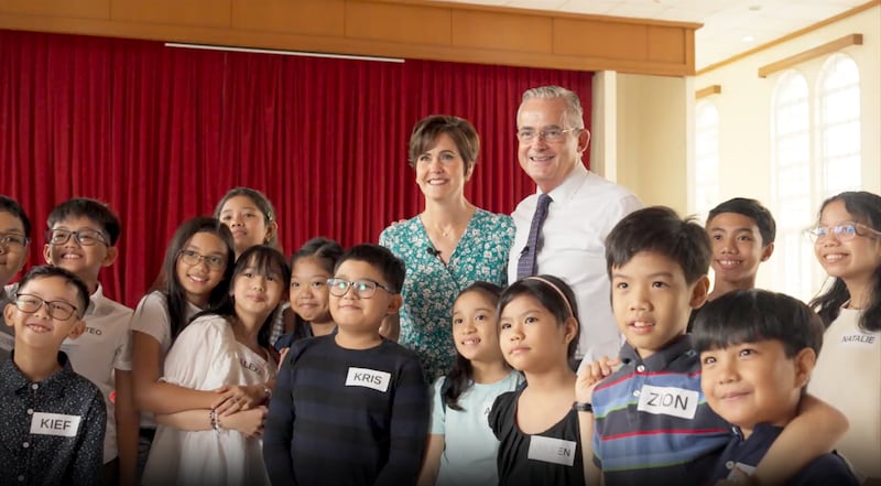 El élder Patrick Kearon y la hermana Jennifer Kearon sonríen con aproximadamente una docena de niños en Filipinas durante la Amistad sin Fronteras de septiembre de 2025.