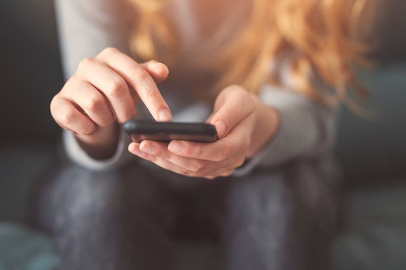 Una mujer joven mira su teléfono.
