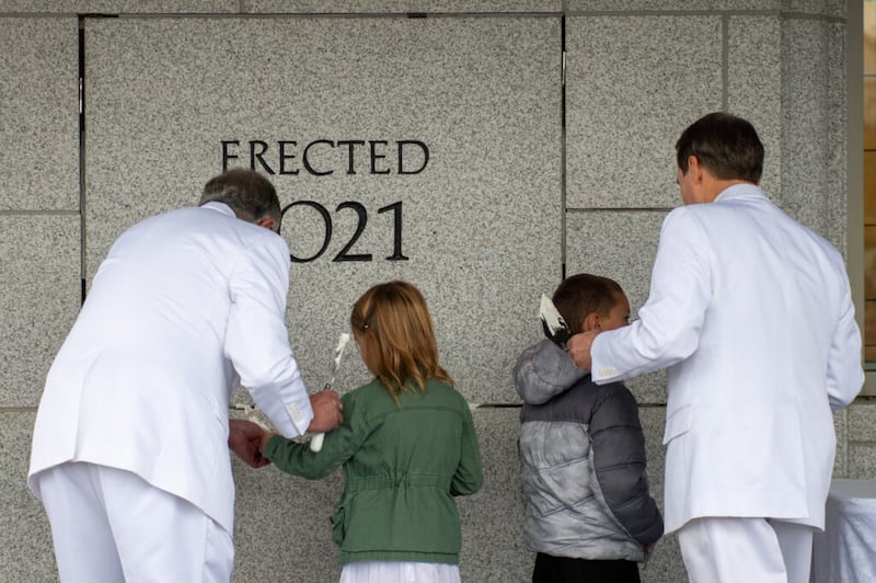 El élder Neil L. Andersen, a la izquierda, y el élder Gary B. Sabin, a la derecha, ayudan a dos niños a sellar la piedra angular durante la ceremonia de dedicación el domingo, 7 de noviembre de 2021, del Templo de Pocatello, Idaho de La Iglesia de Jesucristo de los Santos de los Últimos Días.