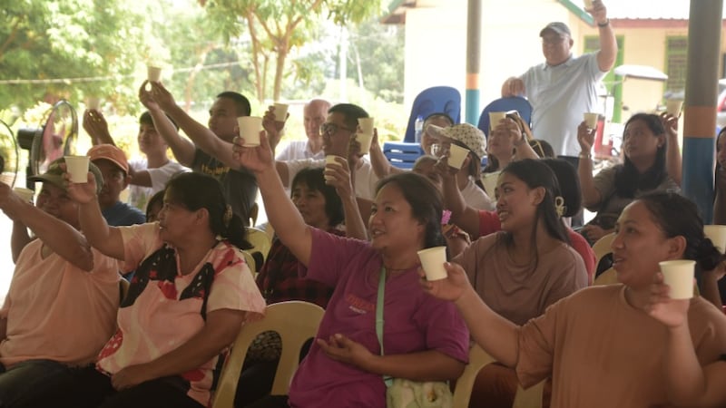 Miembros de la comunidad levantan sus vasos en señal de celebración mientras prueban agua limpia en Filipinas el 23 de abril de 2026.