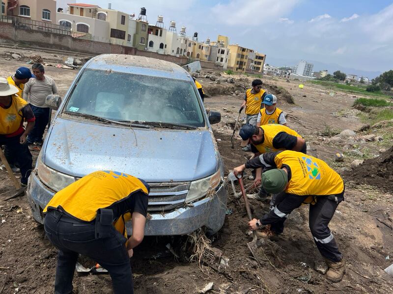 Los voluntarios de servicio de La Iglesia de Jesucristo de los Santos de los Últimos Días se reúnen para limpiar el lodo alrededor de un automóvil después de las inundaciones en Arequipa, Perú. Los deslizamientos de lodo comenzaron después de las lluvias torrenciales del 19 de febrero de 2026.
