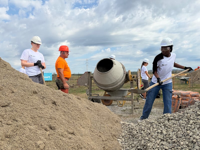 Adultos jóvenes preparan concreto bajo la dirección de un profesional de construcción de Hábitat para la Humanidad Rumania durante un proyecto de servicio de una semana en Berceni, Rumania, en agosto de 2026.