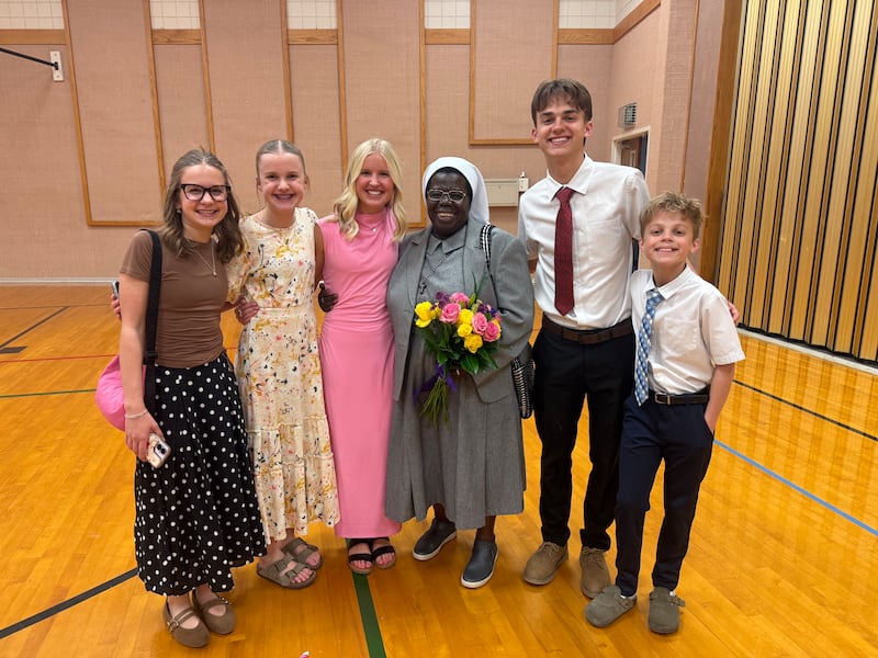 Cinco adultos jóvenes y adolescentes se toman una foto con la hermana Rosemary Nyirumbe después de un devocional el 8 de marzo de 2026 en Norman, Oklahoma.