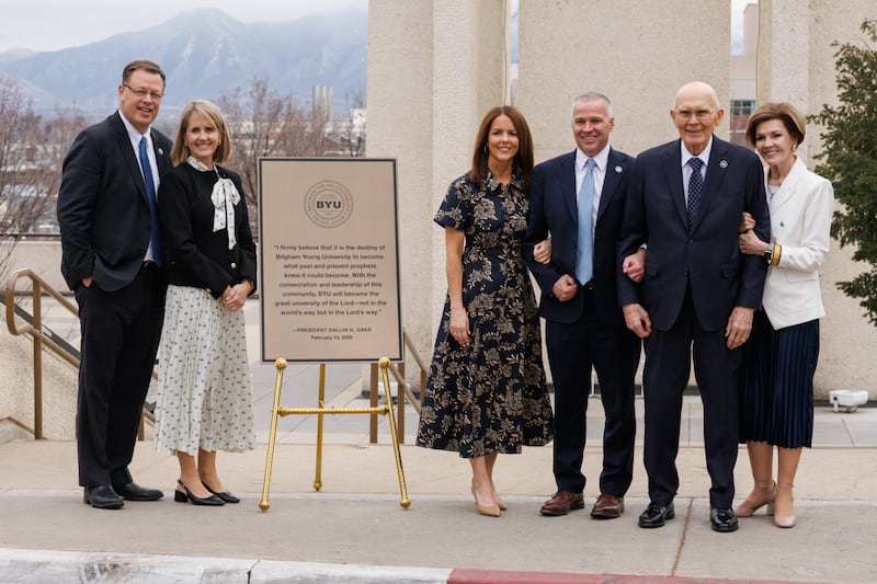 El presidente Dallin H. Oaks, la hermana Kristen M. Oaks, el presidente de la Universidad Brigham Young, C. Shane Reese, la hermana Wendy Reese, el élder Clark G. Gilbert y la hermana Christine Gilbert, cerca de la torre de campanas Carillon junto a una nueva placa con una cita del presidente Oaks que se colocará en la base de la torre en Provo, Utah, el 10 de febrero de 2026,