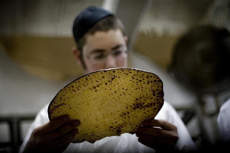 Un hombre judío ultraortodoxo examina una matzá, un pan sin levadura tradicional hecho a mano para la Pascua.