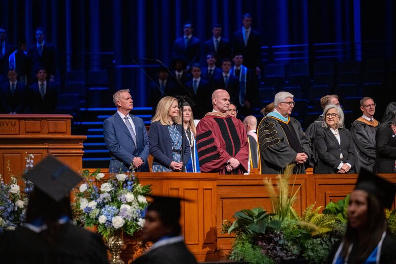 De derecha a izquierda: la hermana Filomena Teixeira, el élder José L. Teixeira, el presidente de BYU–Idaho Alvin F. Meredith III y la hermana Jennifer Meredith se ponen de pie mientras los graduados ingresan al auditorio del Centro de BYU–I para la ceremonia de graduación el viernes 10 de abril de 2026, en Rexburg, Idaho.