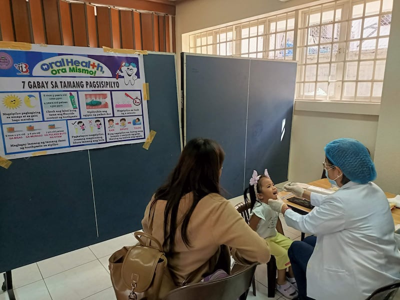 Un trabajador de la salud revisa los dientes de una niña durante un examen realizado en el centro de estaca Caloocan Filipinas el 24 de enero de 2026.