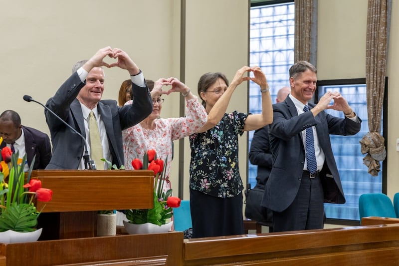 El élder David A. Bednar, la hermana Susan Bednar, la hermana Lynette Cook y el élder Carl B. Cook hacen señales de corazón con las manos hacia los jóvenes adultos solteros en Kinsasa, República Democrática del Congo, el sábado 14 de marzo de 2026.