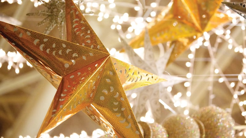 Adornos navideños de estrellas doradas cuelgan como decoraciones para celebrar la Navidad. Las estrellas se utilizan a menudo en las decoraciones navideñas para representar la Estrella de Belén.