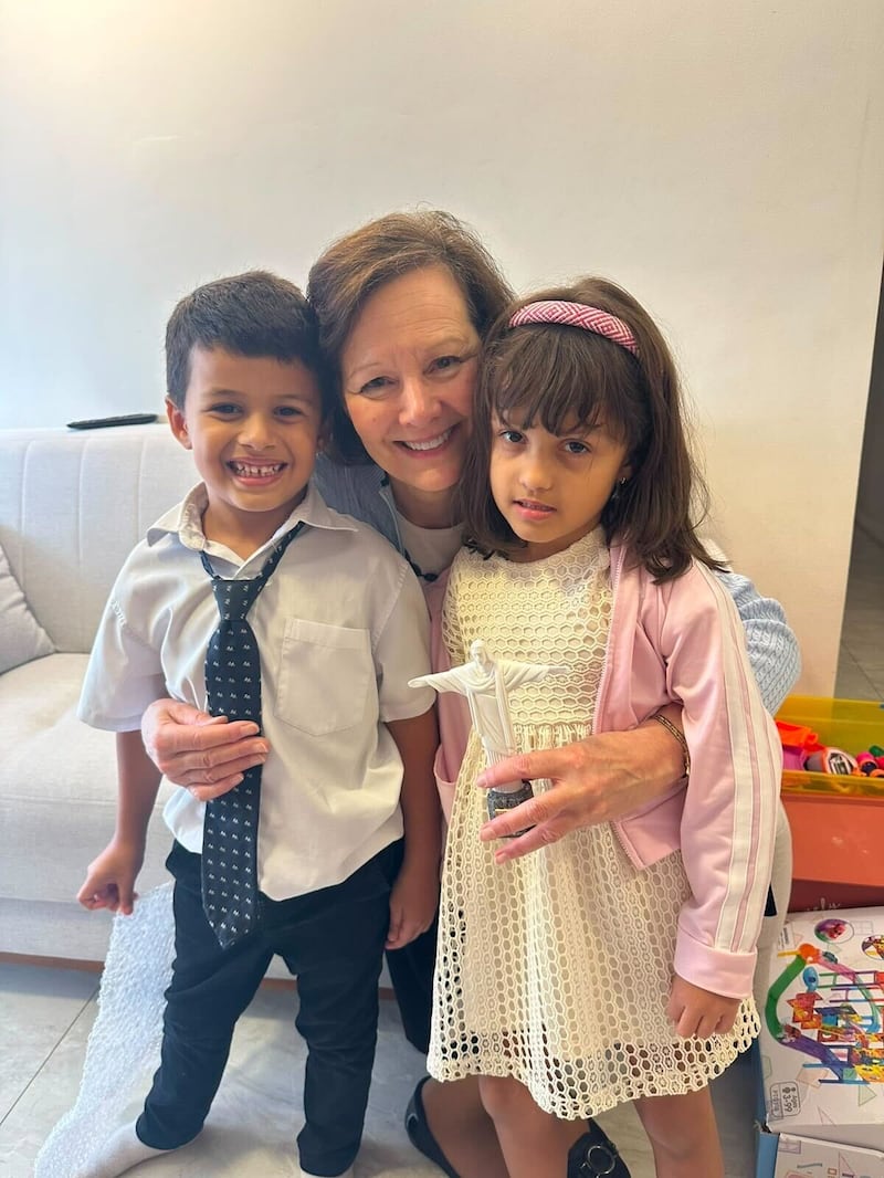 La Presidenta General de la Primaria Susan H. Porter, en el centro, se toma una fotografía con dos niños en Brasil, sábado, 13 de junio de 2026.