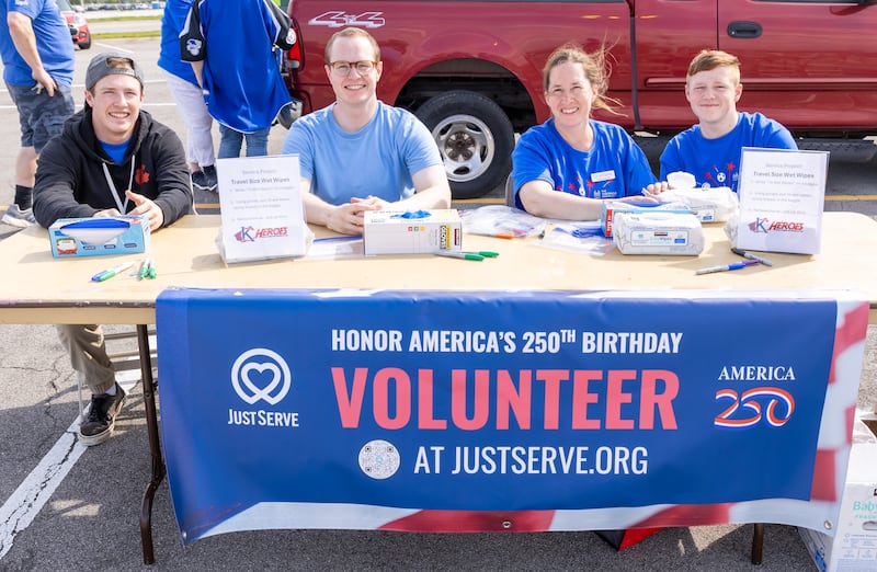 Cuatro voluntarios atienden el puesto de America 250 y JustServe en un evento previo al partido de los Kansas City Royals en Kansas City, Misuri, el jueves 9 de abril de 2026.