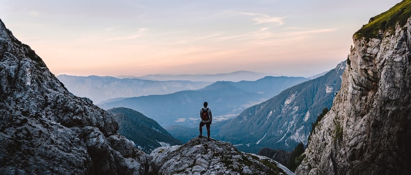 Un excursionista hace una pausa mientras sube Mangart Peak en Eslovenia al amanecer.