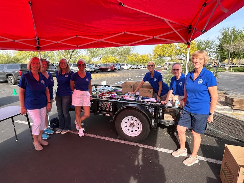 Los voluntarios del evento "5K to Feed the 5k" están de pie junto a un remolque lleno de alimentos donados en Anthem, Arizona, el 28 de marzo de 2026.