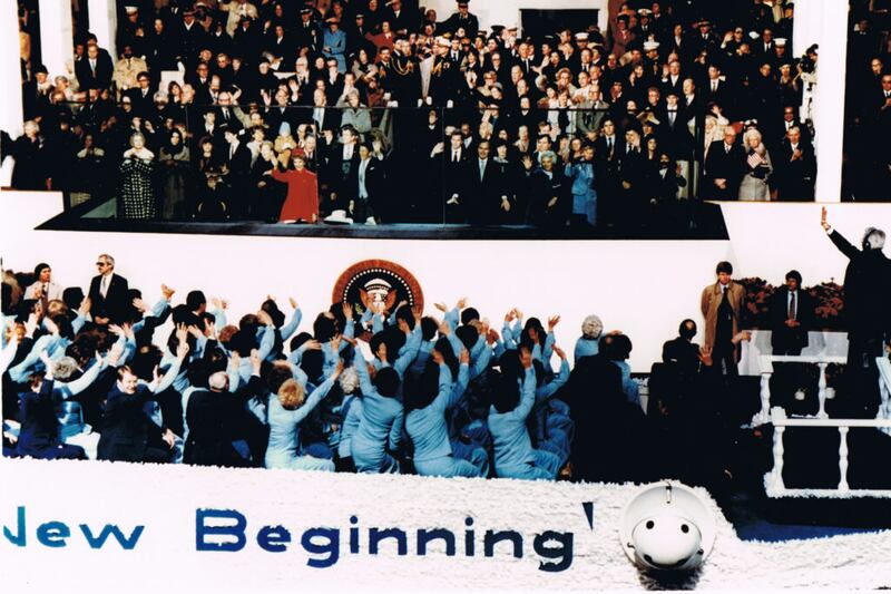 Tabernacle Choir members wave as they sit on a float as it passes a viewing area for officials.