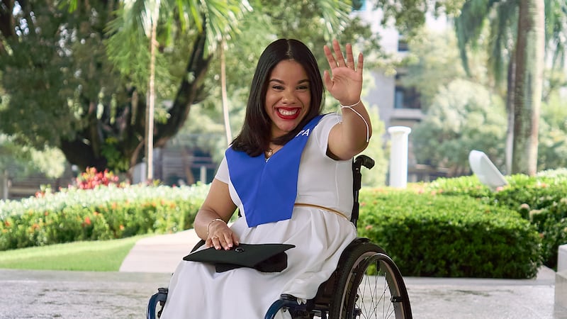 Sidney Peralta saluda a la cámara después de recibir un título en psicología industrial de la Universidad Abierta para Adultos.