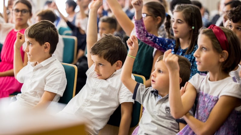 Los niños de la Primaria levantan sus manos en un devocional con la hermana Tracy Y. Browning en Milán, Italia.