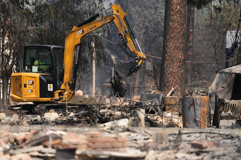 Cuadrillas trabajan cerca de varias casas quemadas después de que un incendio forestal azotara la parte noroeste de Spokane, Washington, el martes, 4 de agosto de 2026.