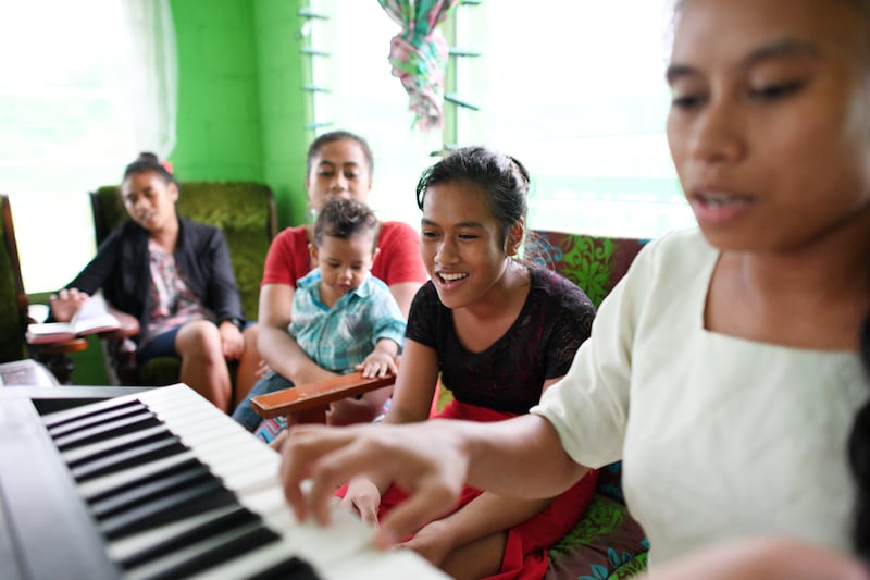 Una familia canta en casa mientras una hija toca el teclado.