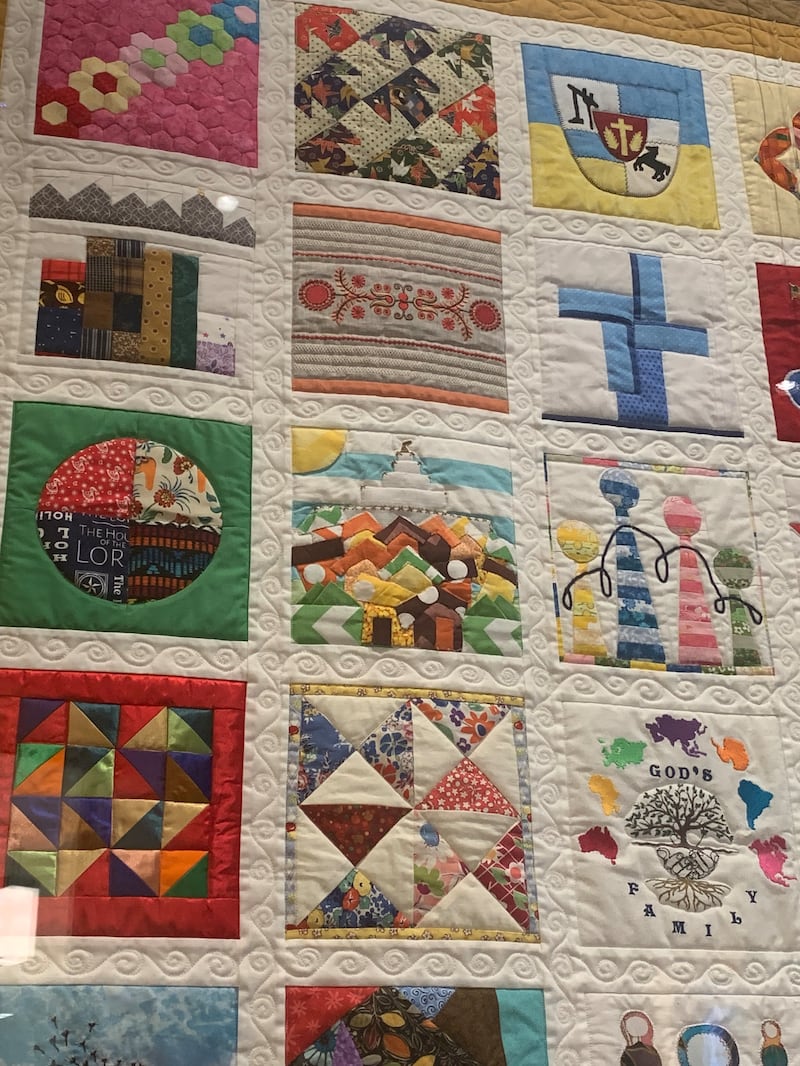 Una vista de cerca muestra bloques cosidos individualmente en "The Family Quilt" en exhibición en el Centro de Visitantes de Temple Square en Salt Lake City en junio de 2026.