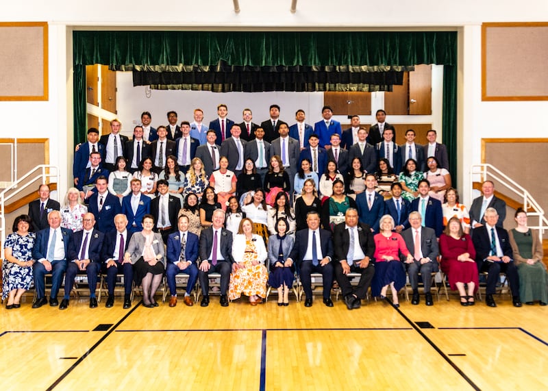 Los misioneros de la Misión California Oakland/San Francisco posan para una foto grupal frente al escenario de una capilla durante una conferencia de zona en 2025.