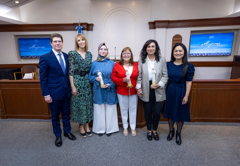 El élder Alan R. Walker, la hermana Inés Walker, Sümeyra Nur Korkur, Cecilia Blanco de Di Lascio, Silvina Chemen y Jorgelina Benavidez posan juntas para una foto después de la ceremonia "Mujeres que Iluminan" en Buenos Aires, Argentina, el 19 de marzo de 2026.