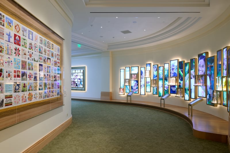 Las paredes del nivel inferior del Centro de Visitantes de la Plaza del Templo en Salt Lake City contienen video, fotos, audio y "The Family Quilt" (La Colcha Familiar). Las puertas se abrieron al público el 18 de mayo de 2026.
