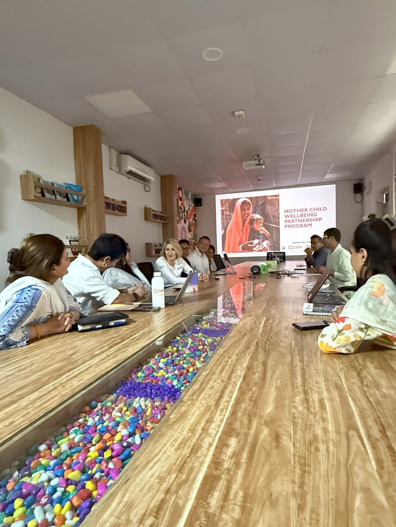 La Presidenta Johnson y otras personas están sentadas en una mesa larga mientras se reúnen en Katmandú, Nepal.