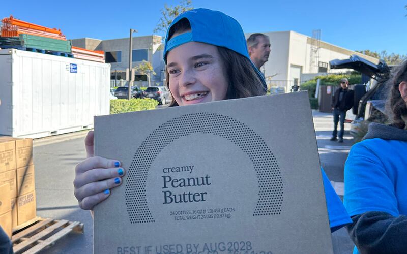 Lacey Smith, una joven voluntaria de JustServe, ayuda a mover cajas de una donación de alimentos de America250 de La Iglesia de Jesucristo de los Santos de los Últimos Días a tarimas para su entrega a casi una docena de diferentes organizaciones benéficas en el área de Irvine, California, el sábado 21 de febrero de 2026.