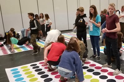 Unos jóvenes participan de un juego de Twister con temática de historia familiar, como parte de una actividad de descubrimiento del evento RootsTech Londres, el 26 de octubre de 2019.