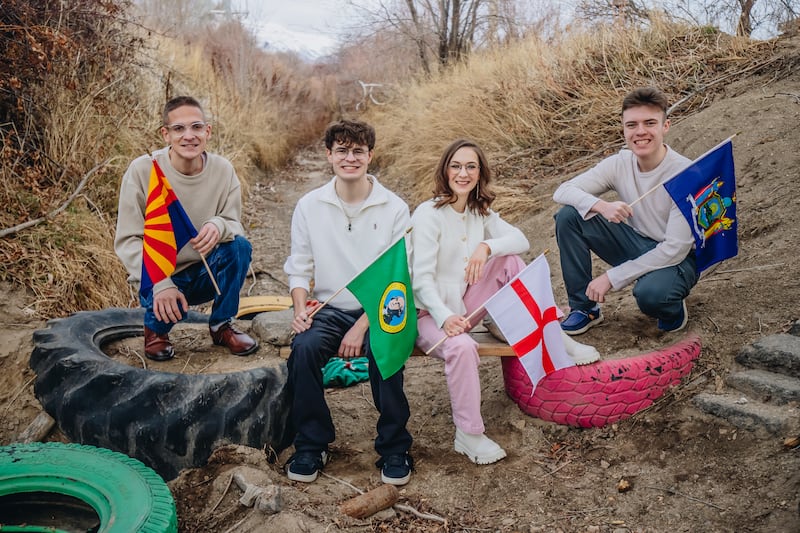 Cuatro hermanos Stoddard que han sido llamados como misioneros sostienen las banderas estatales y nacionales de sus asignaciones misionales en Lehi, Utah, el 15 de febrero de 2026.