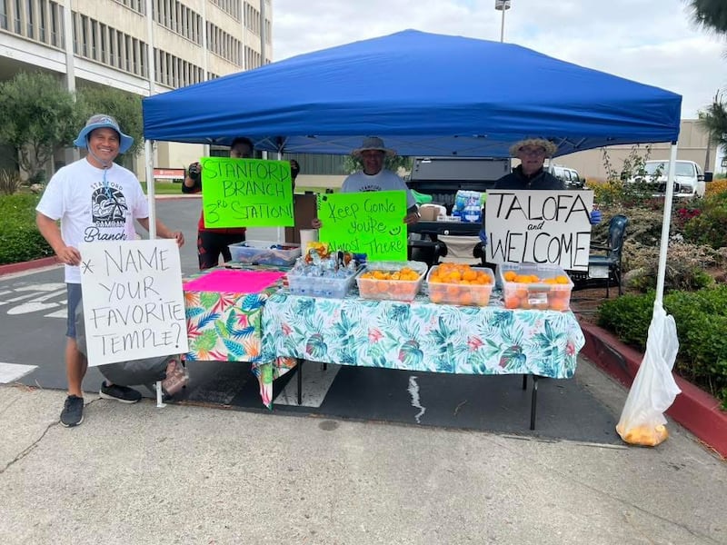 Cuatro personas sostienen carteles de ánimo para caminantes y ciclistas en la Estaca Anaheim California durante una "Caminata al Templo".