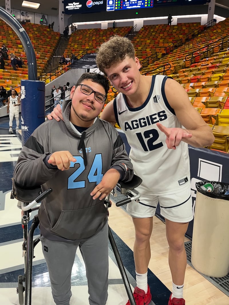 A la izquierda, Dillon Lundahl y su amigo, el jugador de baloncesto de la USU Mason Falslev, aparecen haciendo la seña del toro Aggie después de un partido en el Spectrum en Logan, Utah.