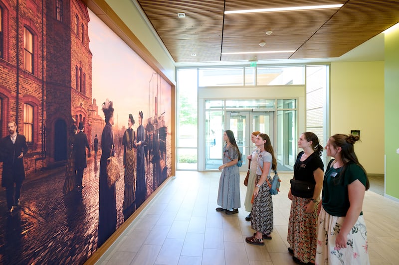 Las hermanas misioneras observan un mural que representa a las primeras hermanas misioneras solteras de esta dispensación, en el Centro de Capacitación Misional de Provo en Provo, Utah, el 19 de junio de 2026.