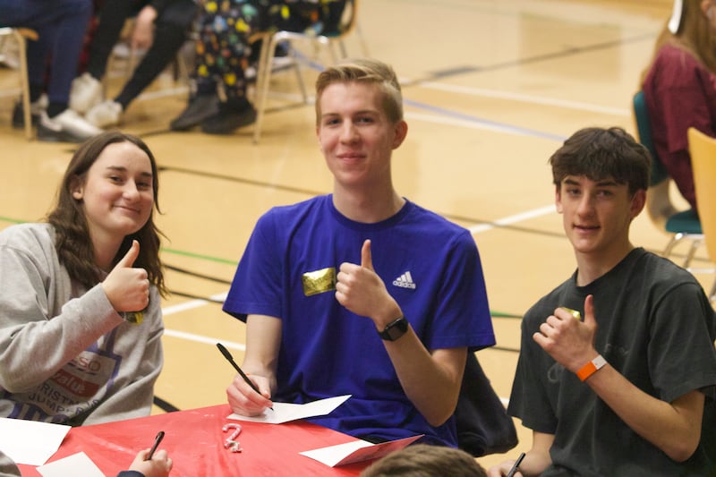 Jóvenes de la Estaca Northampton Inglaterra escriben postales en una mesa durante una actividad de servicio en diciembre de 2024.
