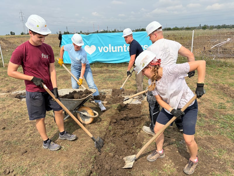 Los voluntarios Santos de los Últimos Días trabajan junto con un profesional de construcción de Hábitat para la Humanidad Rumania para preparar marcos de paredes de madera para hogares en construcción en Berceni, Rumania, en agosto de 2026.