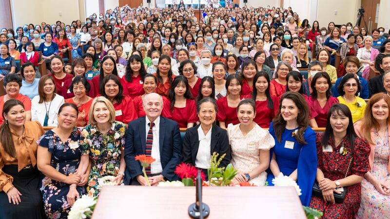 La presidenta general de la Sociedad de Socorro, Camille N. Johnson, y el hermano Doug Johnson se sientan en la capilla de un centro de reuniones con cientos de mujeres en Bangkok, Tailandia.
