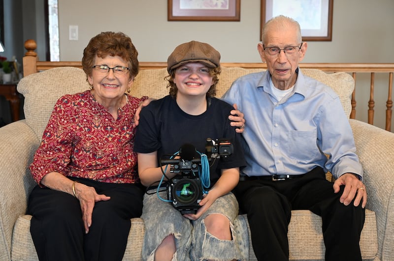 Paige Olsen — ganadora de la categoría de presentación de diseño en el Festival de Cine All-American High School, centro — sonríe para una foto con sus abuelos Linda Mortensen y Ron Mortensen mientras filma un documental sobre la vida de Ron en Perry, Utah, febrero de 2025.