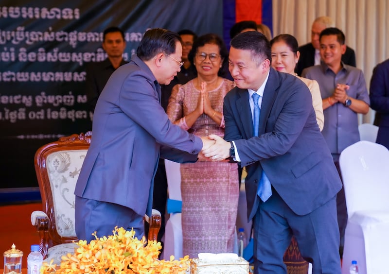El Ministro de Culto y Religión de Camboya, Chay Borin, y el Élder Benjamin M.Z. Tai, Setenta Autoridad General y presidente del Área Asia de la Iglesia, se dan la mano al final de la ceremonia de entrega en el distrito de Dambae, Camboya, el 7 de junio de 2025.