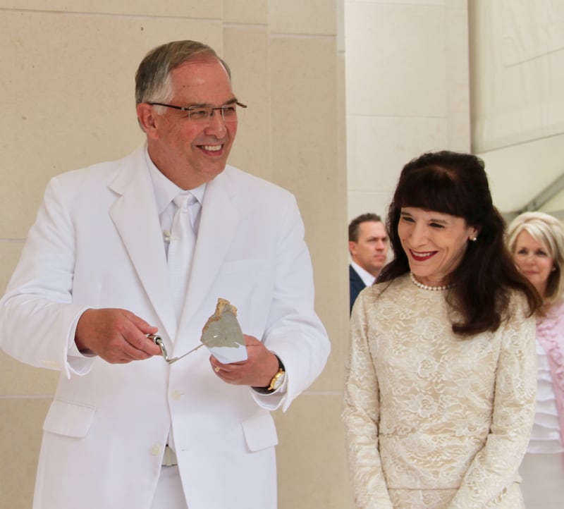 El élder Neil L. Andersen, del Quórum de los Doce Apóstoles, habla a los miembros antes de aplicar cemento en la ceremonia de coronación de la dedicación del Templo de Lisboa Portugal, el domingo, 15 de septiembre de 2019. Lo acompaña su esposa, la hermana Kathy Andersen.